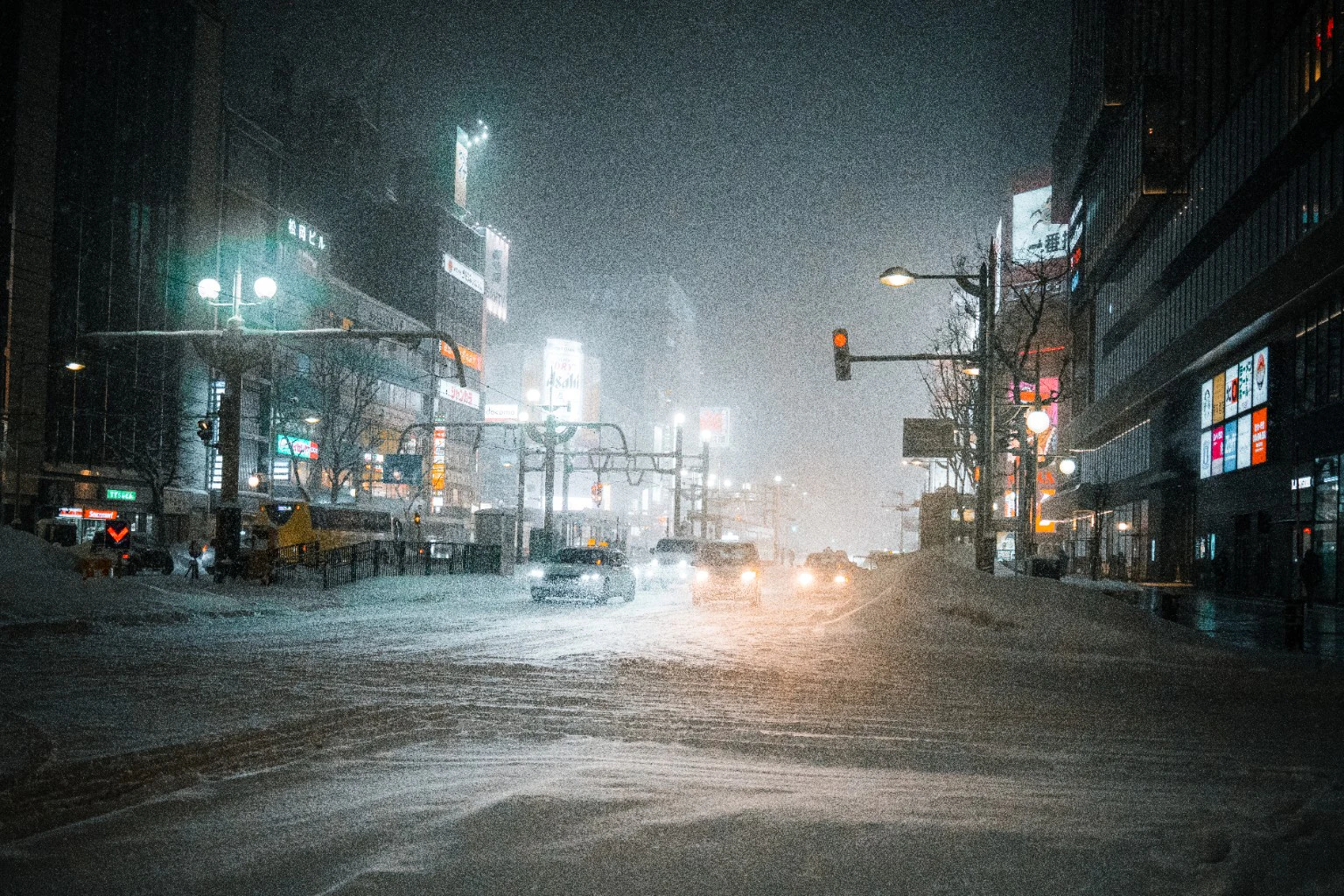 A car crossing a snowy city street at night